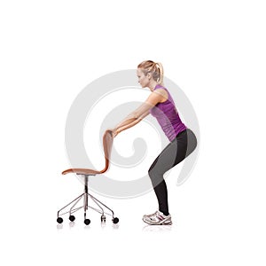 Office, chair and woman in squat, exercise or crouch in white background or studio. Person, stretching and workout with