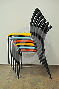 Office chairs are put with color seats in a stack. Side view