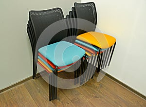 Office chairs are put with color semi-soft seats in a stack in a