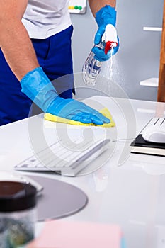 Office Cleaning Service. Janitor Spraying Desk