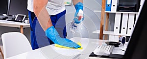 Office Cleaning Service. Janitor Spraying Desk