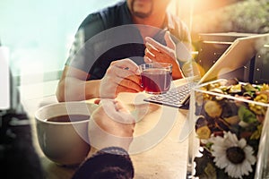 Office coffee break with two designer colleagues sitting chatting over cups of coffee,flowers vase,digital tablet docking smart k