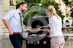 Office colleagues grilling sausages at bbq after work