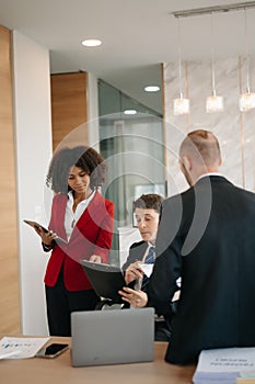 Office colleagues have a casual discussion. During a meeting in a conference room, a group of business teem sit in the conference