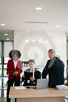 Office colleagues have a casual discussion. During a meeting in a conference room, a group of business teem sit in the conference