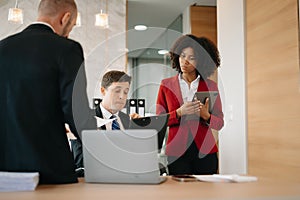 Office colleagues have a casual discussion. During a meeting in a conference room, a group of business teem sit in the conference