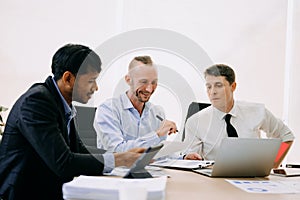 Office colleagues have a casual discussion. During a meeting in conference room, a group of business teem sit in the conference