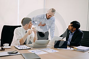 Office colleagues have a casual discussion. During a meeting in conference room, a group of business teem sit in the conference