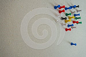 Office colorful thumbtacks pushpins on a pining white tan wall