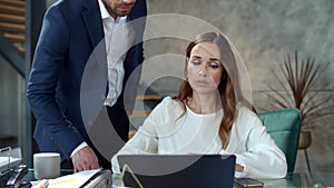 Office coworkers discussing business in office. Man correcting papers.