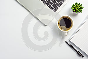 Office desk with coffee cup, blank notebook, black pen, laptop computer and cactus pot