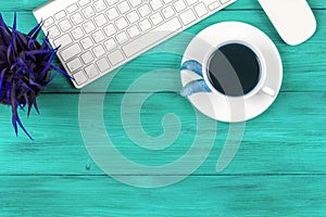 Office desk with copy space. Digital devices wireless keyboard and mouse on blue wooden table with cup of fresh coffee, top view