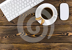 Office desk with copy space. Digital devices wireless keyboard and mouse on dark wooden table with cup of coffee, top view