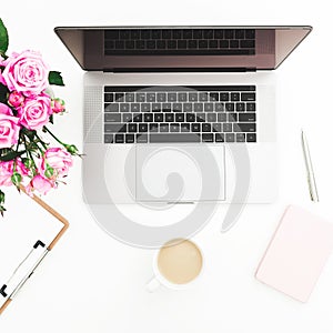 Office desk with female workspace with laptop, pink roses bouquet, coffee mug, pink diary on white background. Flat lay. Top view.