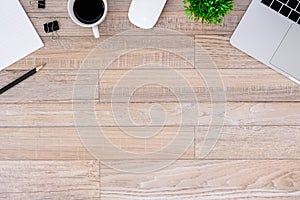 The office desk flat lay view with laptop, mouse, tree, black clip, coffee cup, notebook, pencil on wood texture background