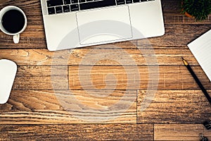 The office desk flat lay view with laptop, mouse, tree, black clip, coffee cup, notebook, pencil on wood texture background