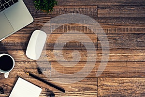 The office desk flat lay view with laptop, mouse, tree, black clip, coffee cup, notebook, pencil on wood texture background