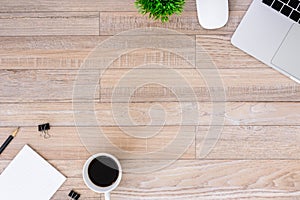 The office desk flat lay view with laptop, mouse, tree, black clip, coffee cup, notebook, pencil on wood texture background