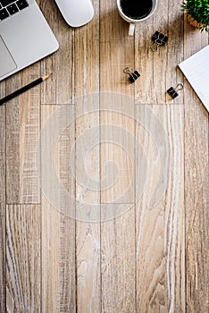 The office desk flat lay view with laptop, mouse, tree, black clip, coffee cup, notebook, pencil on wood texture background