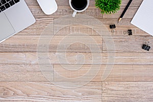 The office desk flat lay view with laptop, mouse, tree, black clip, coffee cup, notebook, pencil on wood texture background