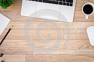 The office desk flat lay view with laptop, mouse, tree, black clip, coffee cup, notebook, pencil on wood texture background