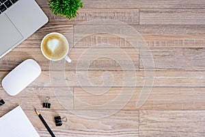 The office desk flat lay view with laptop, mouse, tree, black clip, heart latte coffee cup, notebook, pencil on wood texture