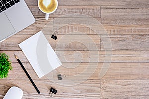 The office desk flat lay view with laptop, mouse, tree, black clip, heart latte coffee cup, notebook, pencil on wood texture