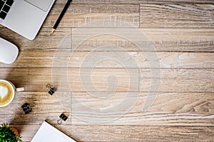 The office desk flat lay view with laptop, mouse, tree, black clip, heart latte coffee cup, notebook, pencil on wood texture