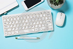 Office desk with keyboard,  succulent and pen on blue background.