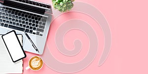 Office desk with laptop computer, Blank screen smart phone, cup of coffee, pen, Notebook on pink background