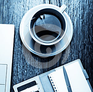 Office desk with laptop computer, planner, cup of tea