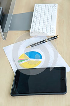 Office desk with monitors keyboards iPad and the different graphs on paper