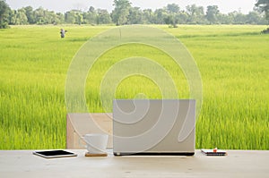 Office desk with notepad, notebook, pencil and coffee cup over rice farm background.