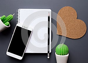 Office desk table with blank notepad, smartphone and cacti