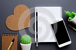 Office desk table with blank notepad, smartphone and cacti