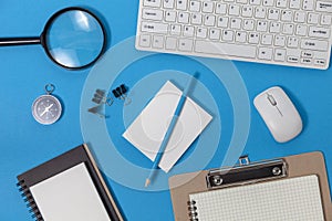 Office desk table of Business workplace and business objects of keyboard,mouse,white paper,notebook,pencil,compass on blue