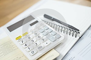 Office desk table calculator with notepad book and black pen.