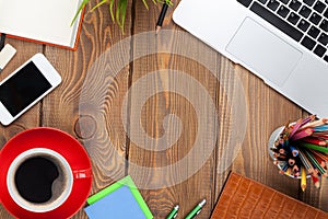 Office desk table with computer, supplies, coffee cup and flower