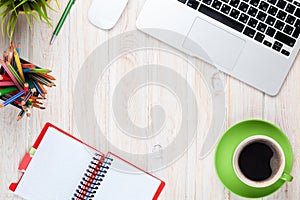 Office desk table with computer, supplies, coffee cup and flower