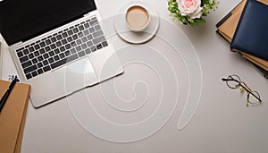 Office desk table with computer, supplies, flower and coffee cup. Top view with copy space