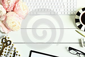 Office desk table with items, pastel pink peony flowers and cup of coffee.