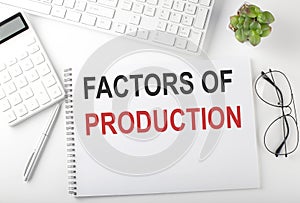 Office desk table with keyboard, notepad and calculator. Top view with text FACTORS PF PRODUCTIONS