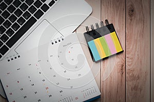 Office desk table with laptop, calendar and indexes sticky note. Top view with copy space