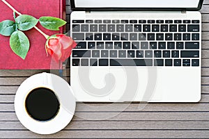 Office desk table with laptop,notebook, coffee cup,red rose