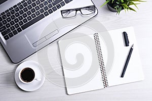 Office desk table with laptop, smart phone, cup of coffee and supplies, on wooden background. Top view with copy space, flat lay