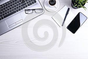 Office desk table with laptop, smart phone, cup of coffee and supplies, on wooden background. Top view with copy space, flat lay