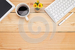 Office desk table with smartphone, pen on notebook, cup of coffee and flower. Top view with copy space (selective focus)..