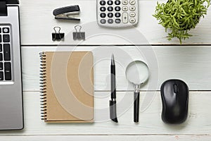 Office desk table with supplies. Top view. Copy space for text. Laptop, blank notepad, pen, magnifying glass, calculator