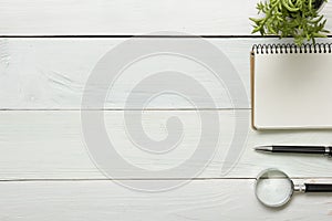 Office desk table with supplies. Top view. Copy space for text. Notepad, pen, magnifying glass, flower