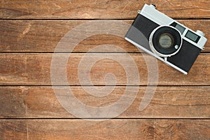 Office desk wooden table with old camera. Top view with copy space. Top view of old camera over wooden table. Retro vintage filter